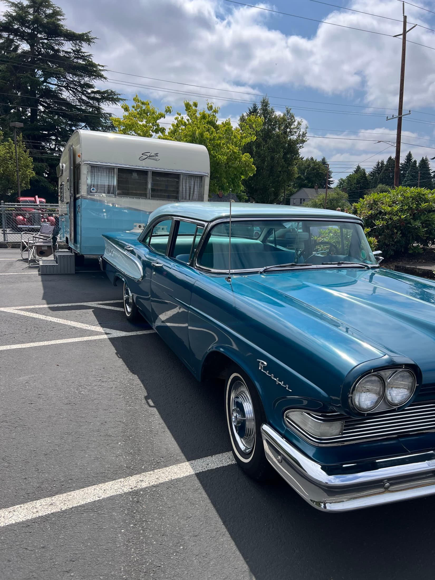 Blue classic car parked near a vintage camper.