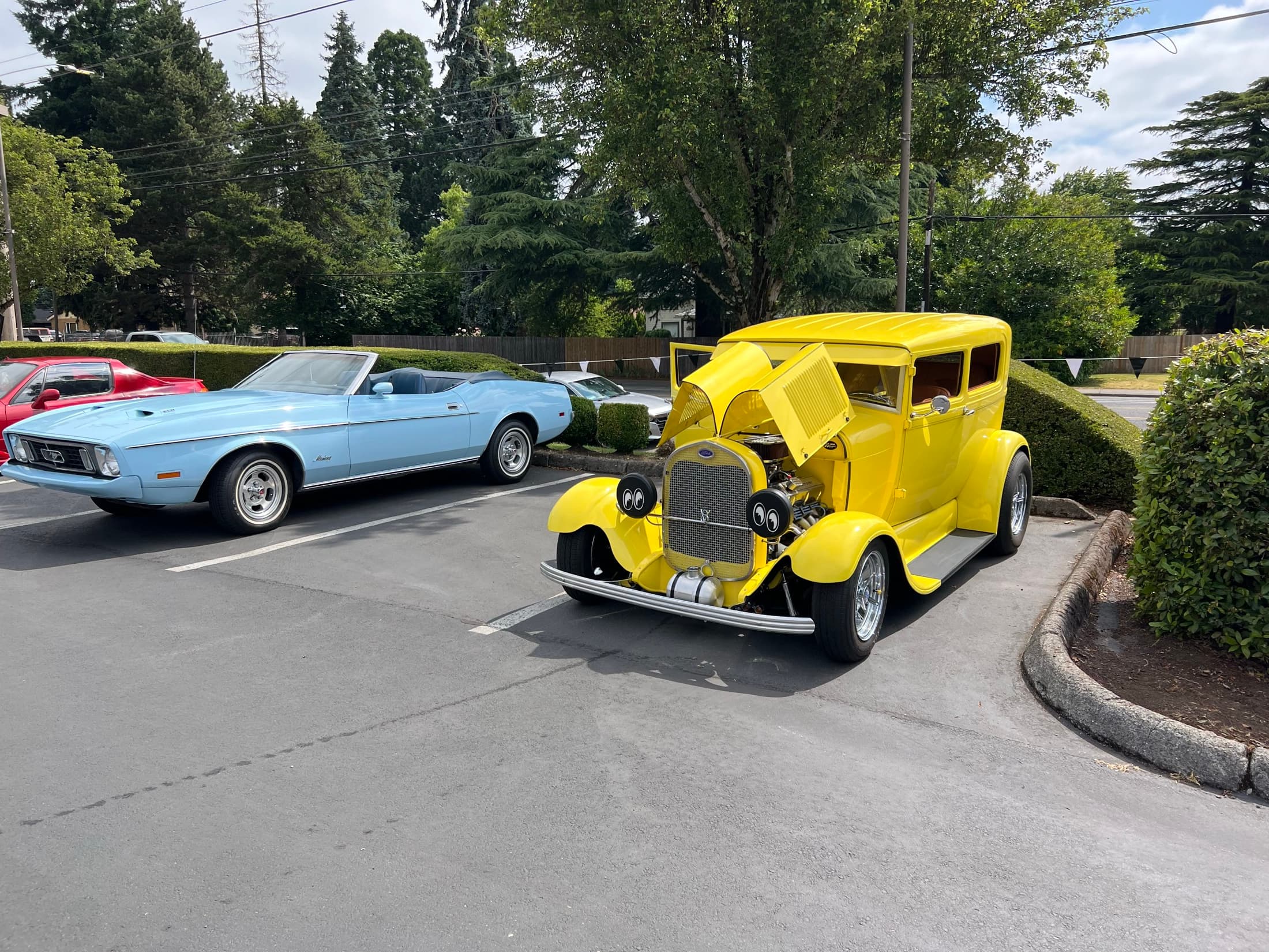 Silver convertible and yellow hot rod in the parking lot.
